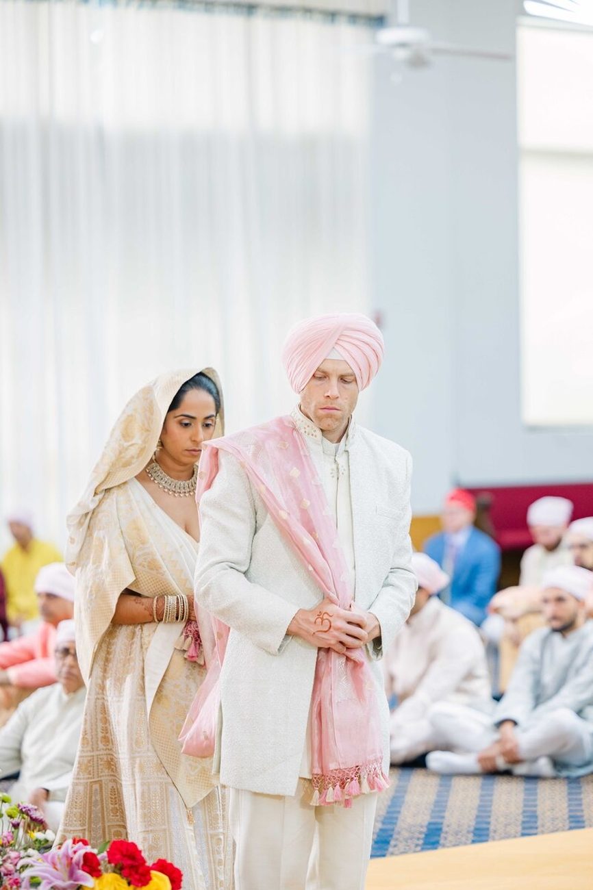 Couple laughing in baraat with friends in turbans
