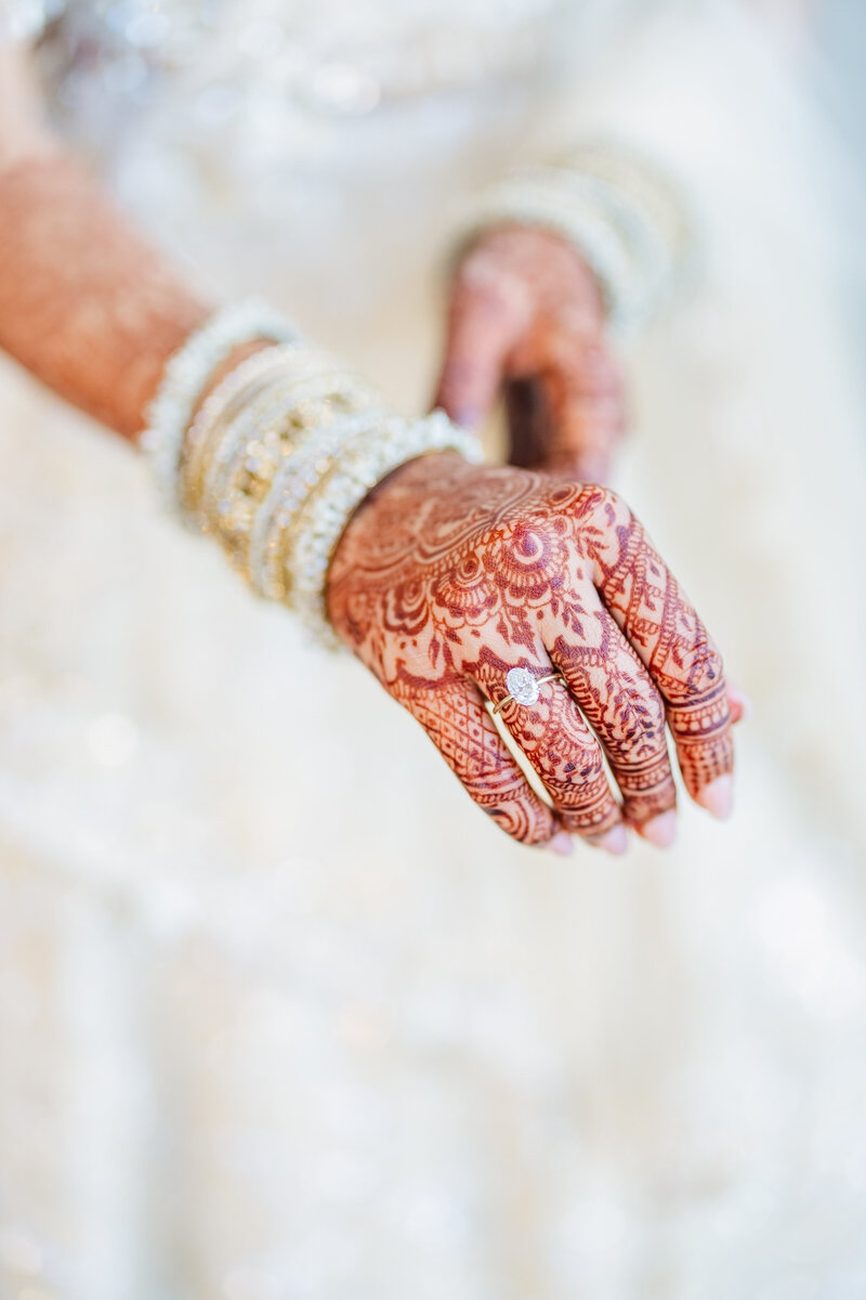 Bride's hand with henna and diamond ring on lace