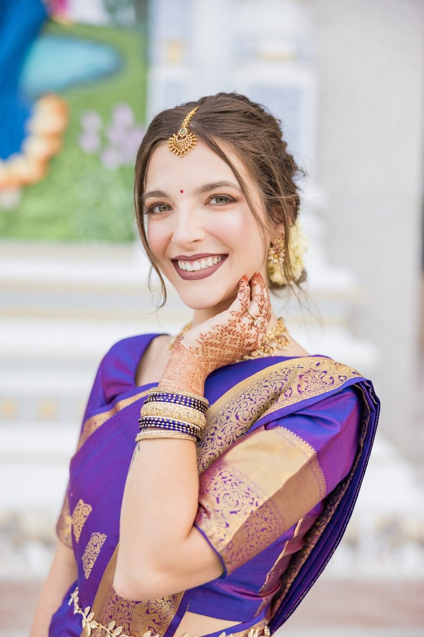Bride smiling in purple silk saree with mehndi