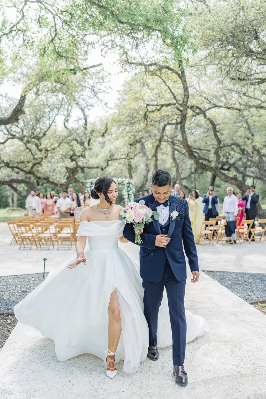 Wedding party cheers under floral arch, green attire