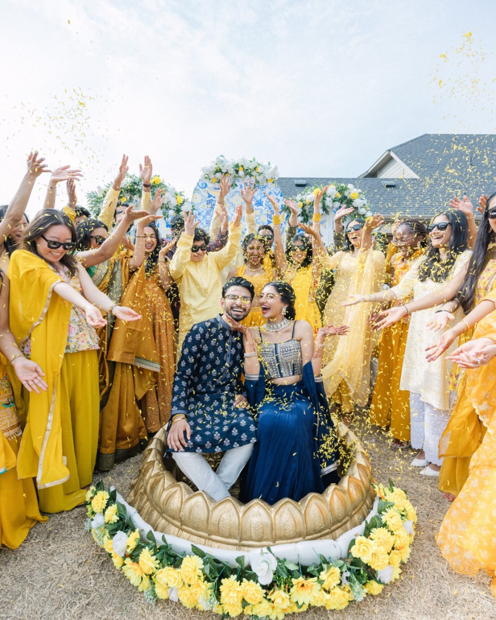 Couple surrounded by family during a vibrant flower-toss celebration